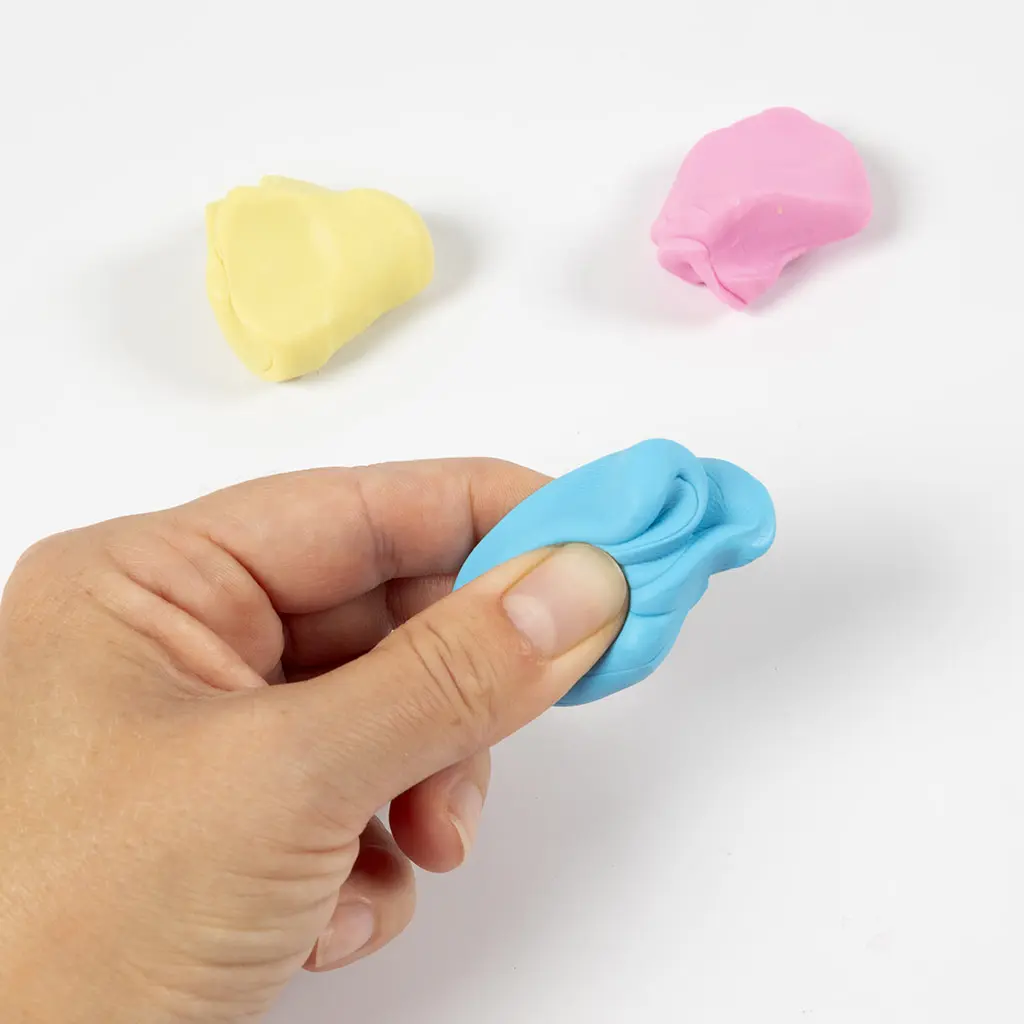 Een hand die een stukje blauwe klei soepel knijpt, met geel en roze klei op de achtergrond.