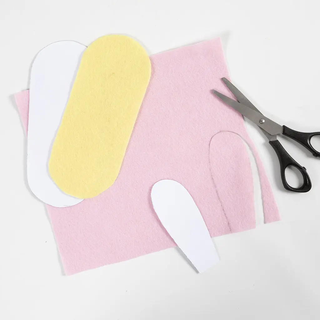 Papieren patronen, vilt in roze en geel, en een schaar op een witte achtergrond.