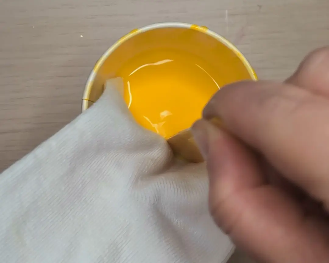 witte sok wordt in de gele textielverf geduwd met een houten stokje