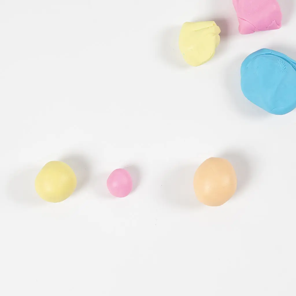 Drie kleine gekleurde bolletjes klei uitgelijnd op een witte ondergrond.