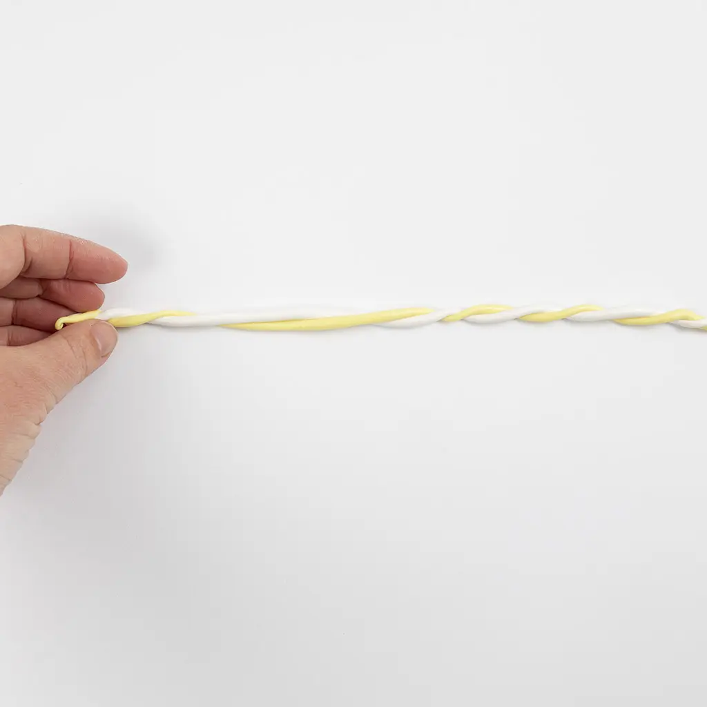 Een witte en een gele kleistring zijn in elkaar gedraaid tot een lang spiraalvormig koord.