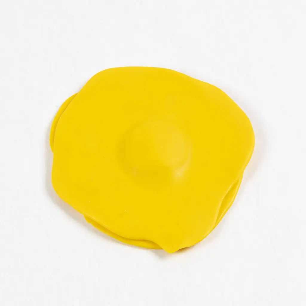 De twee gele kleicirkels zijn op elkaar gestapeld met het kleine bolletje klei ertussen, waardoor er een subtiele, gladde verhoging in het midden ontstaat.