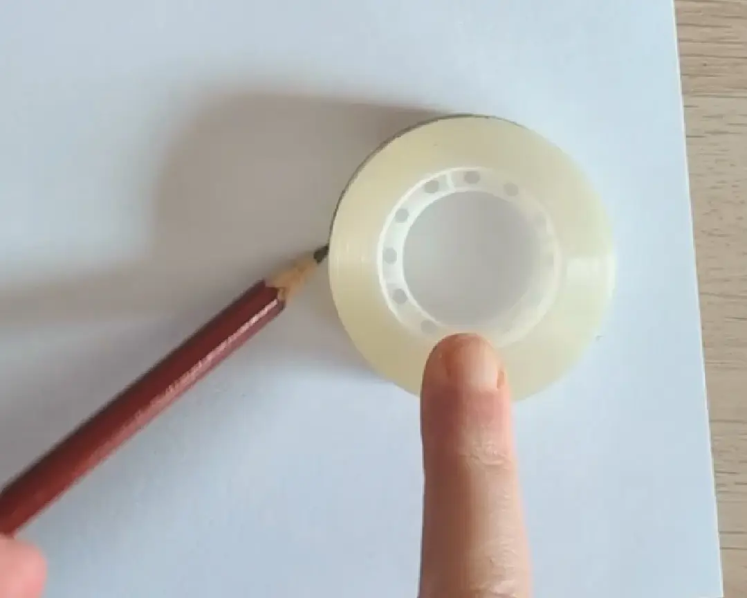 plakbandrol op papier waar een cirkel omheen wordt getekend met potlood.