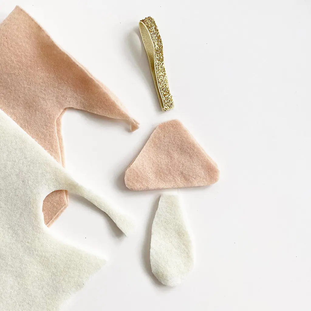 Losse onderdelen van vilt voor het maken van een paddenstoel hanger: een roze hoedje, een wit steelje en een gouden glitterbandje.