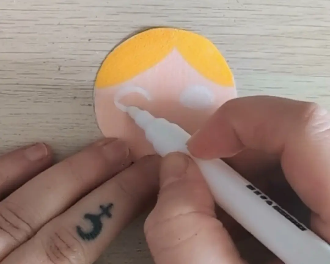 uitgeknipte cirkel wordt ingekleurd tot een gezichtje met een stift.