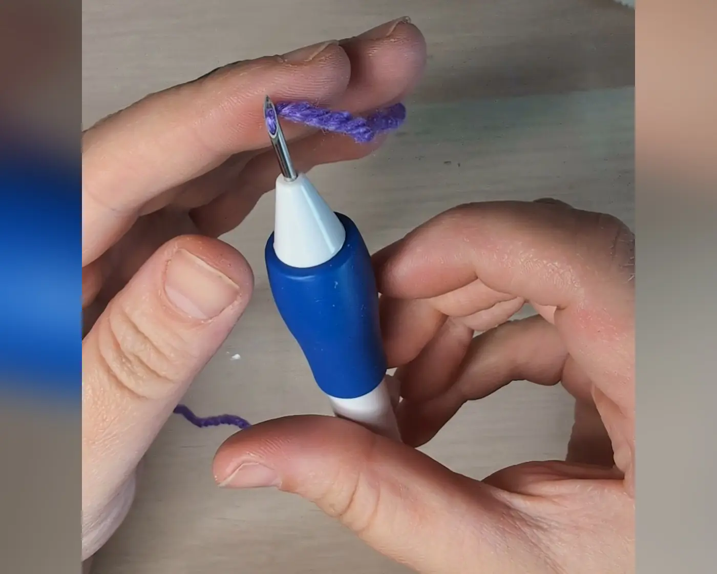 Handen die paars garen door het oog van de punch needle rijgen met een draadrijger