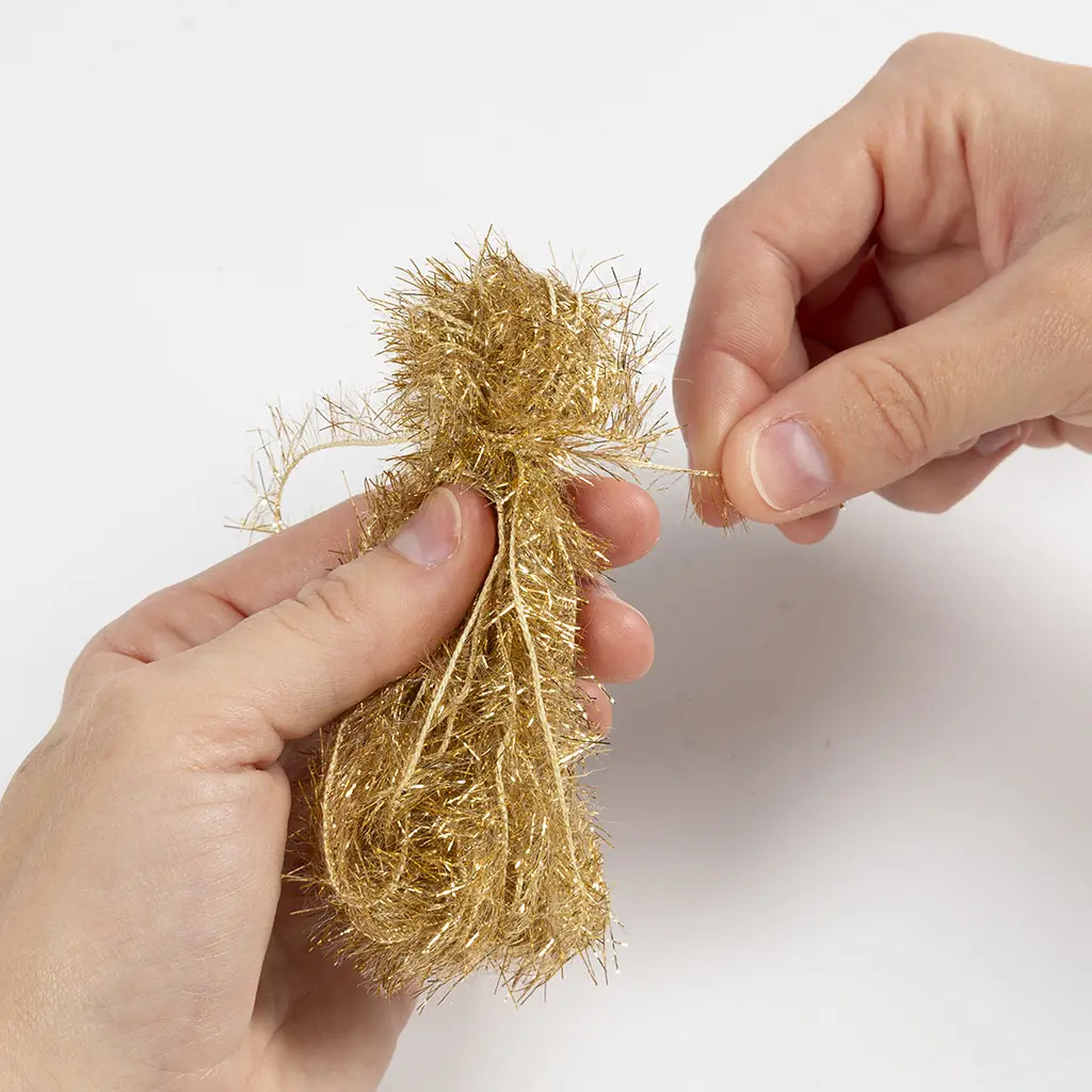 Een los draadje wordt strak om de bundel goud garen gebonden om een kwastje te maken.