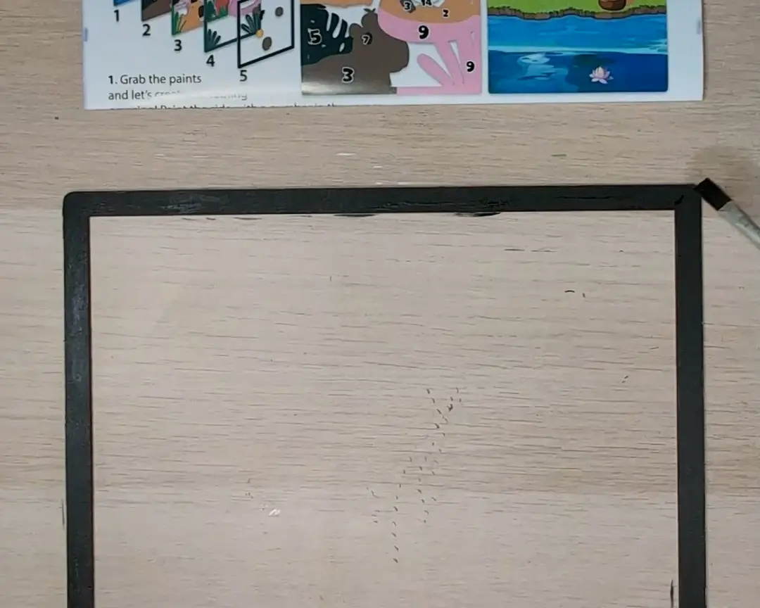 Onbewerkte zwarte houten kaderlaag liggend voor een instructiekaart.