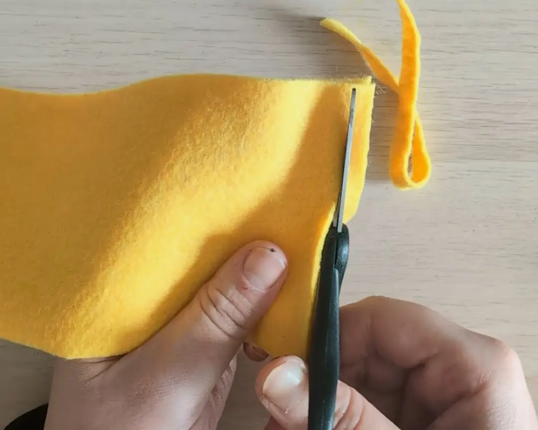 schaar knipt stroken van geel vilt
