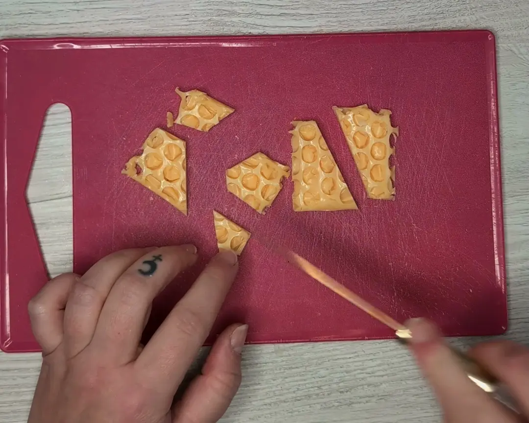 gele zeep in een hanging graat patroon worden in stukjes gesneden op een roze snijplank