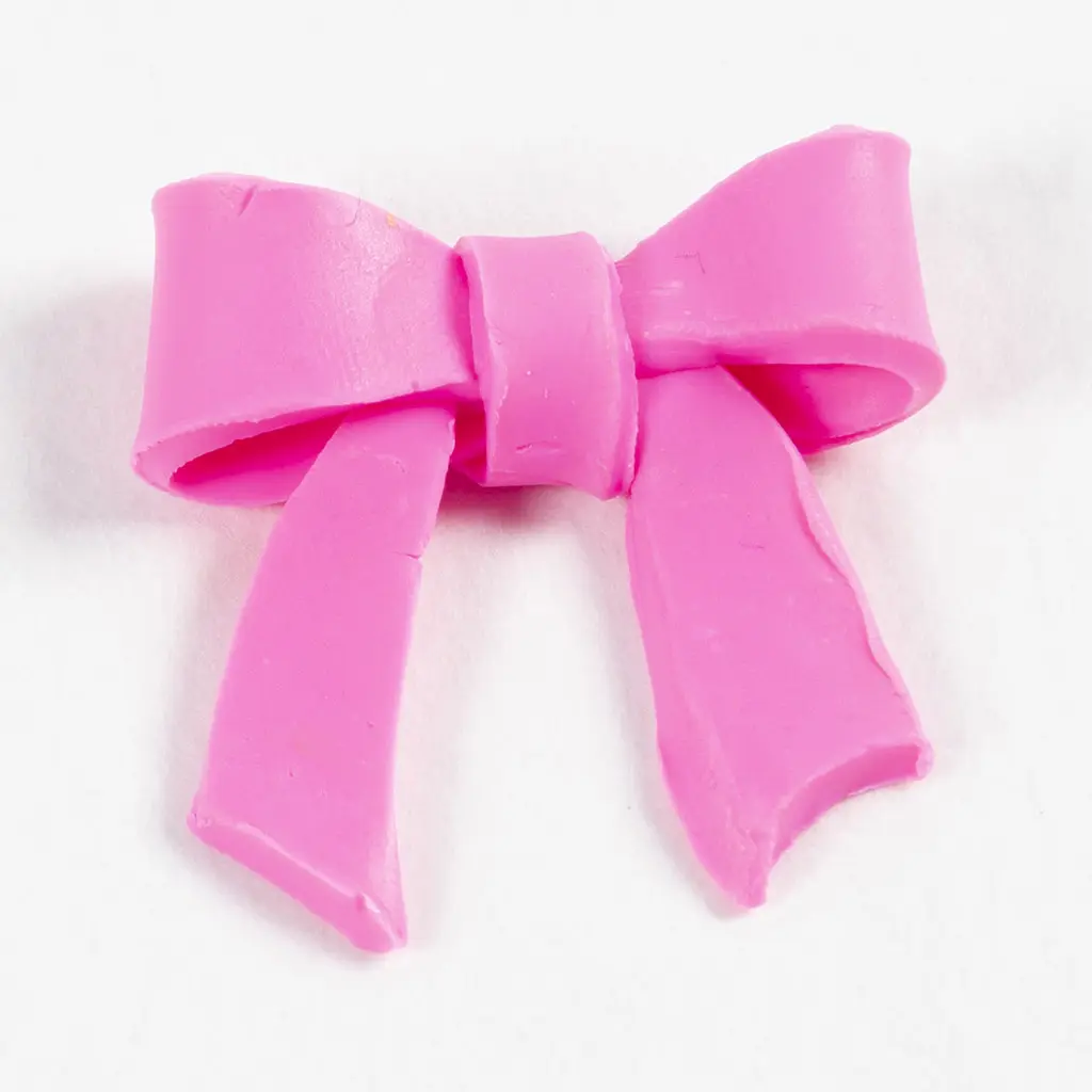Een klein roze rechthoekje van klei is om het midden van de strik gewikkeld om de knoop te vormen, waarmee de vorm van de roze strik compleet is.
