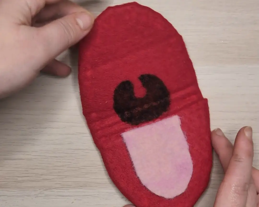 rode vilten ovaal met getekende keel en roze tong.