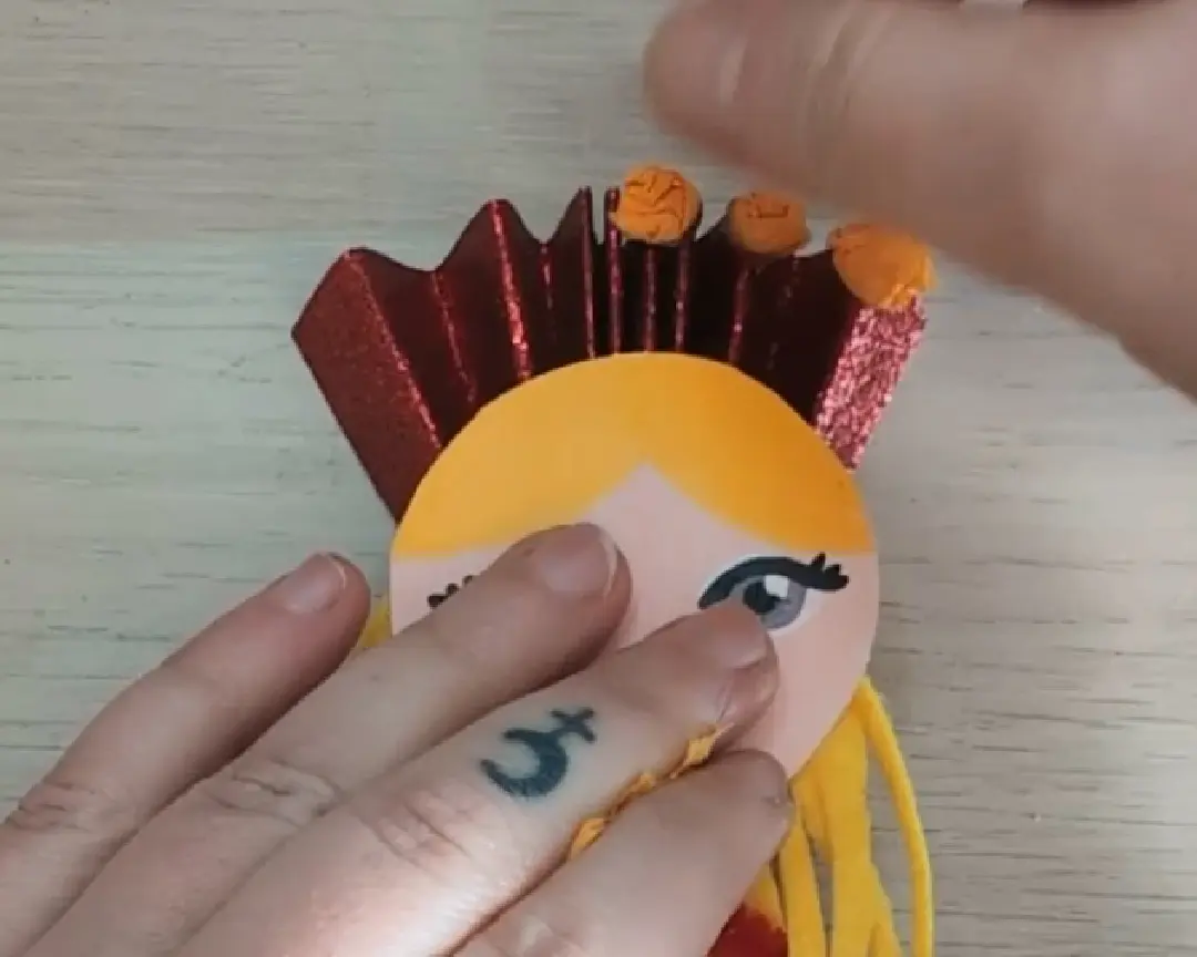 kleine balletjes crêpepapier worden op de bovenkant van het glitterpapier geplakt.