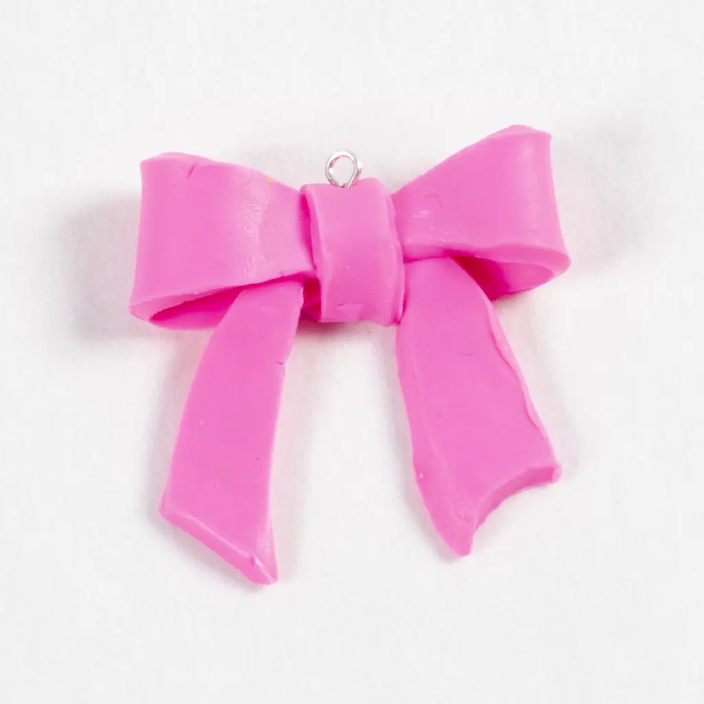 De afgebakken roze kleistrik met een zilverkleurige metalen oogpen die stevig in de knoop aan de bovenkant is bevestigd, klaar om als hanger te dienen.