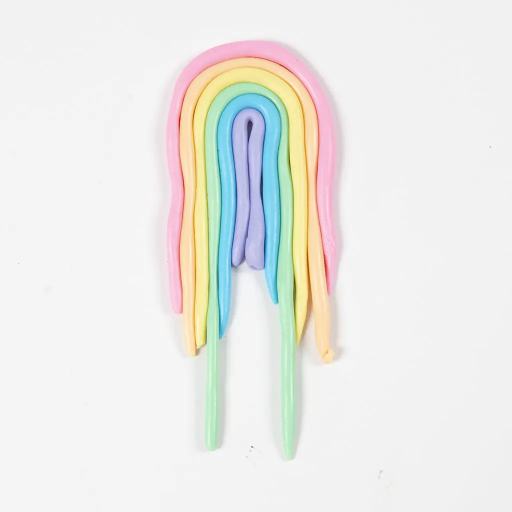 Gekleurde kleiworstjes naast elkaar gebogen in de vorm van een regenboog.