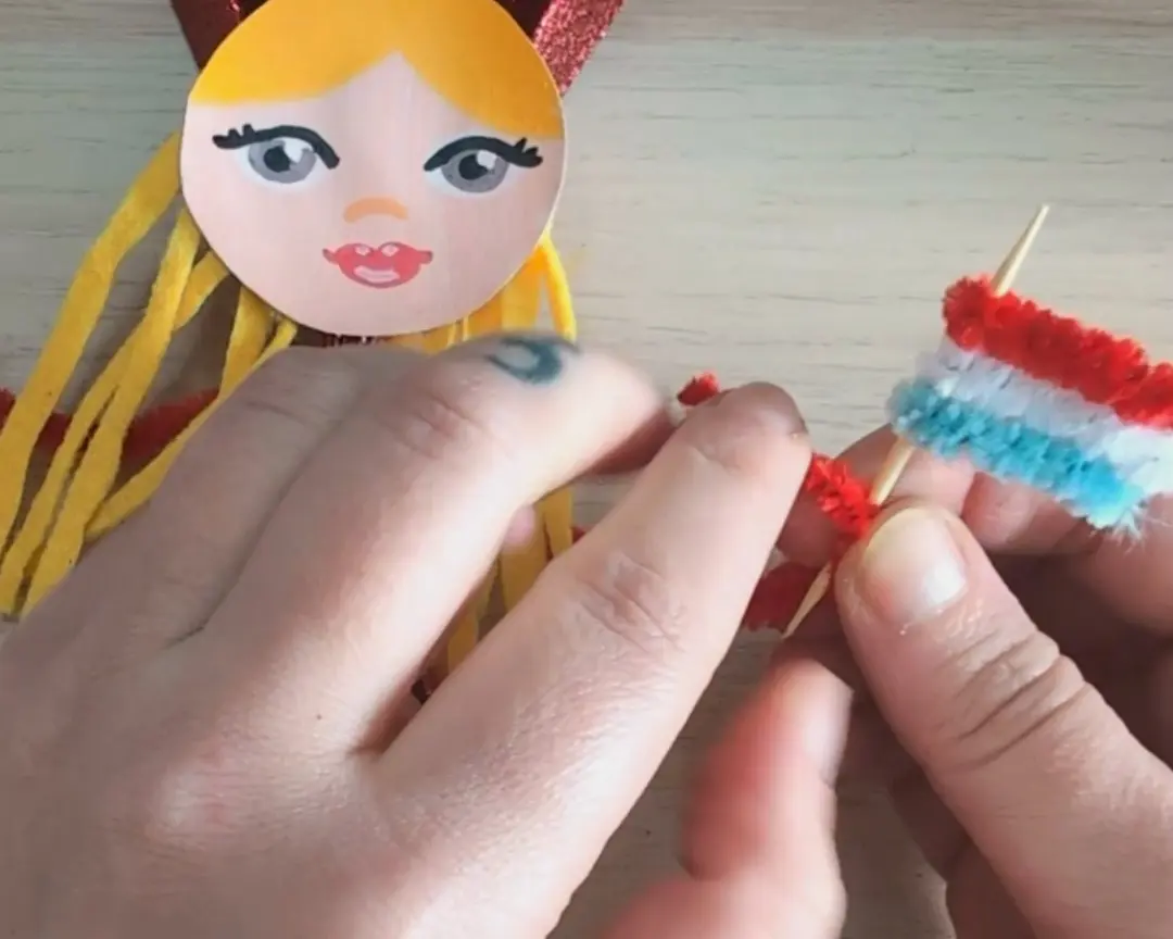 chenilledraad vlaggetje in de arm van het poppetje gedraaid.