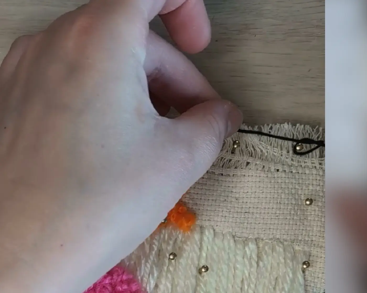 Close-up van een hand die met zwart garen een knoop legt om een spijker.
