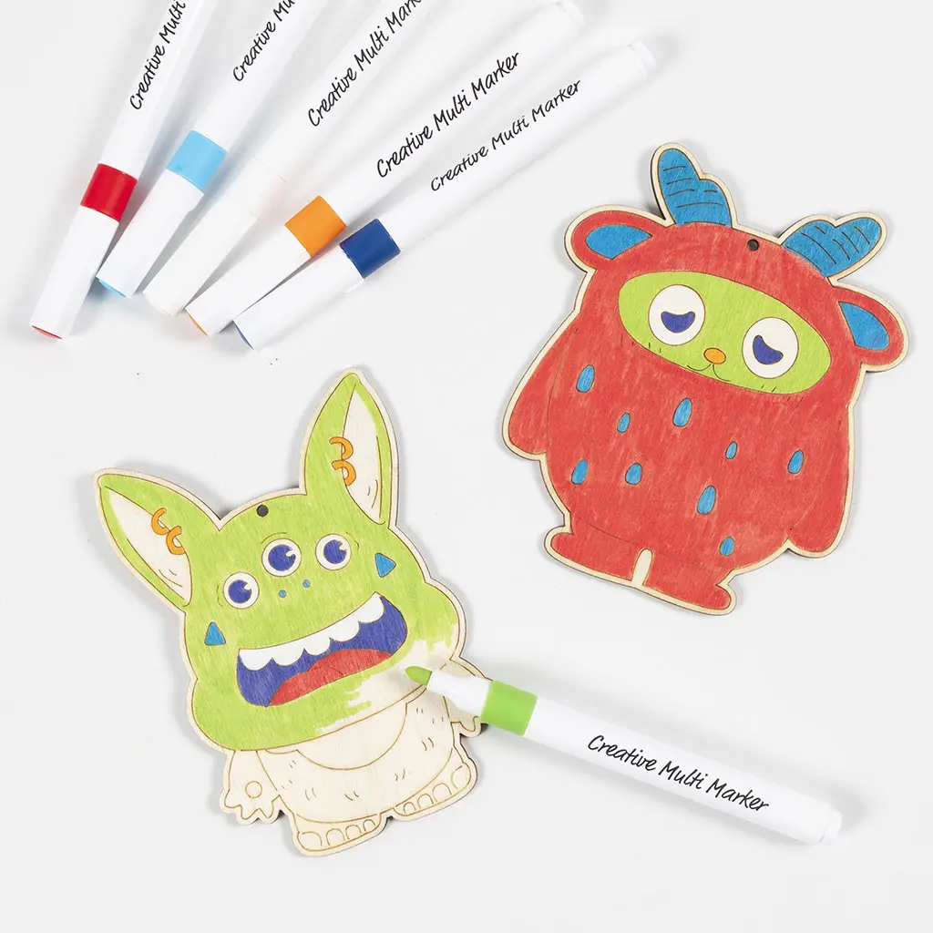 Bovenaanzicht van een nieuwe set houten monsters die worden ingekleurd. Het linker monster heeft drie ogen en wordt met een groene stift ingekleurd. Het rechter monster is felrood met blauwe hoorns. Vijf Creative Multi Markers liggen linksboven uitgewaaierd.