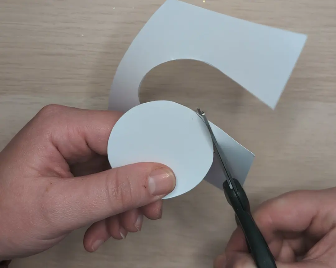 schaar knipt witte cirkel uit papier.