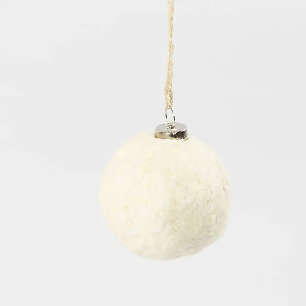 De volledig met papierpulp bedekte kerstbal hangt te drogen aan een jute touwtje op een egale witte achtergrond.