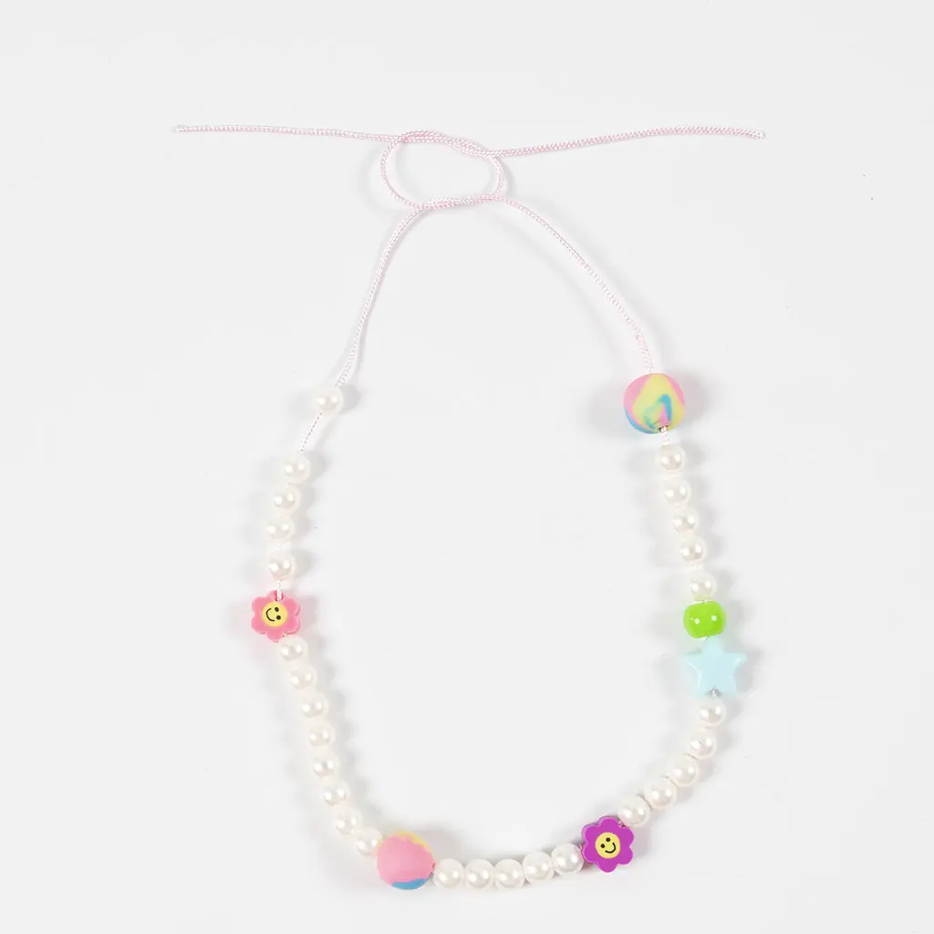 Een halverwege geknoopte parelketting met kleurrijke kleikralen, sterren en smiley-bloemetjes.