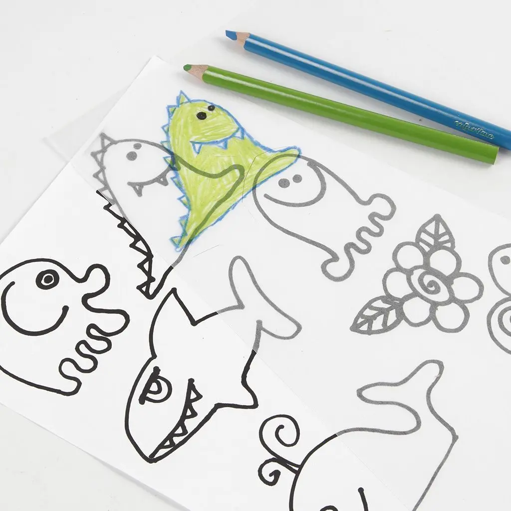 Een vel krimpfolie waarop een groen ingekleurde dinosaurus met blauwe omtrek is getekend, liggend op een wit papier met zwarte lijntekeningen van zeedieren en bloemen. Boven het papier liggen een groene en een blauwe kleurpotlood.