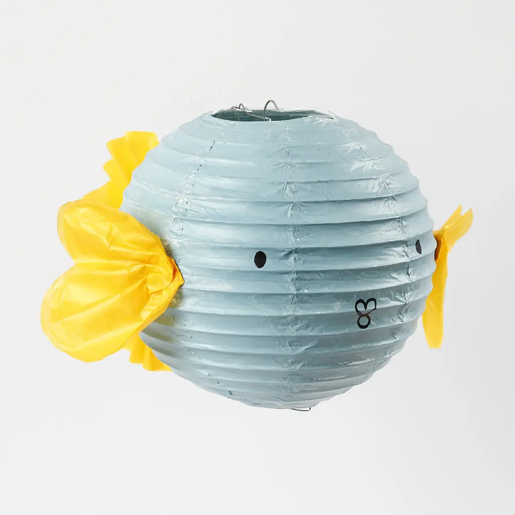 De voltooide blauwe vislampion voorzien van gele zijvinnen, een staartvin en een getekend gezichtje met oogjes en een kussend mondje.