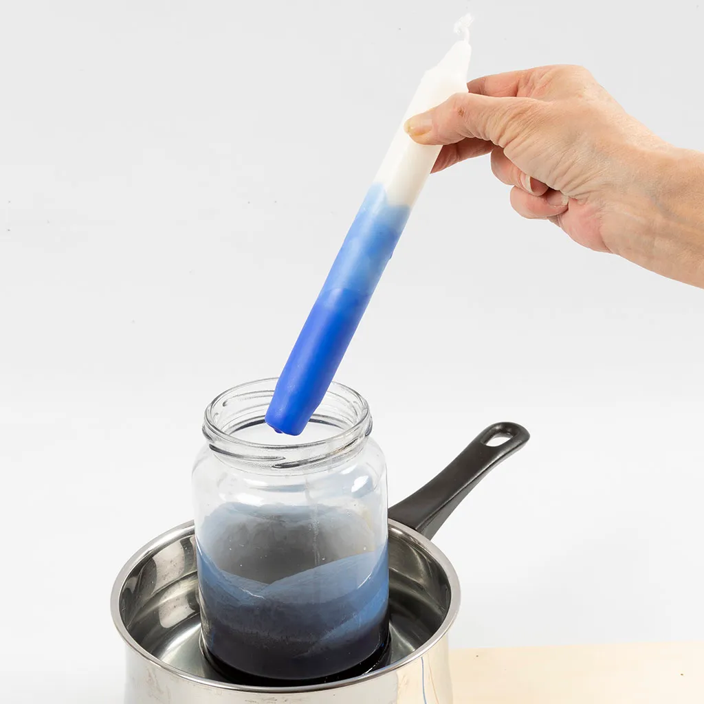 in kleur gedipte kaars boven de glazenpot in een pan