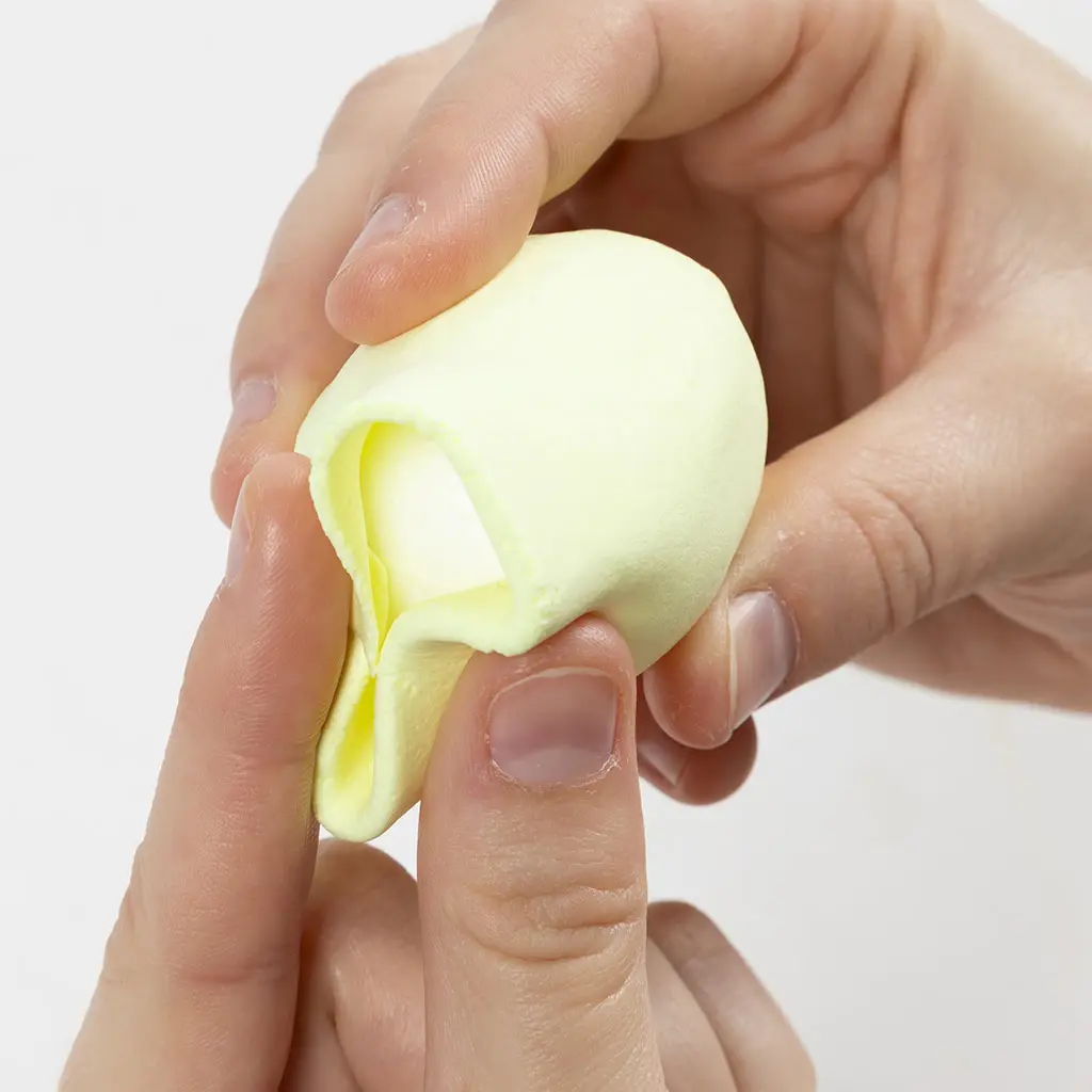 Het dichtknijpen van de overtollige lichtgele klei rondom het piepschuim ei om het volledig te bedekken.