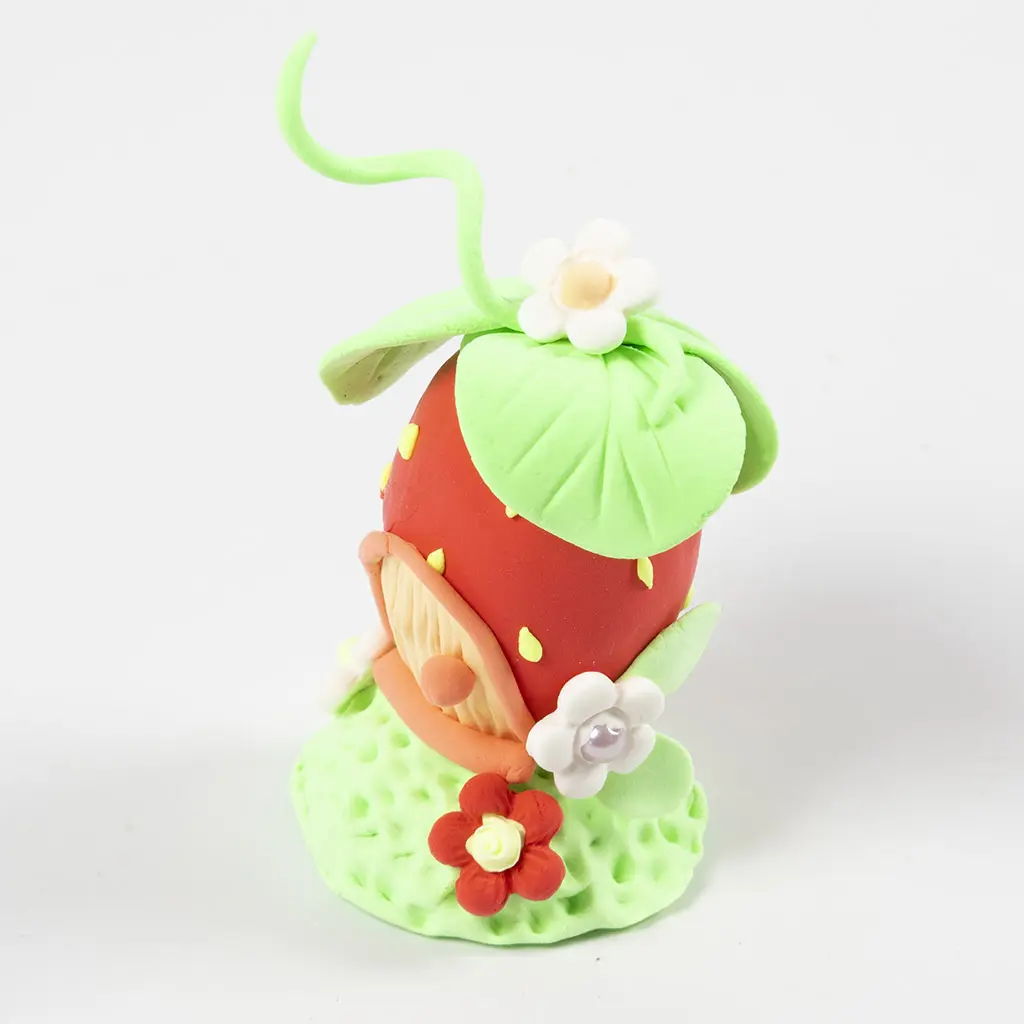 Schuin bovenaanzicht van het afgewerkte aardbeienhuisje met groen bladerdak, een opkrullende stengel en schattige bloemdetails.