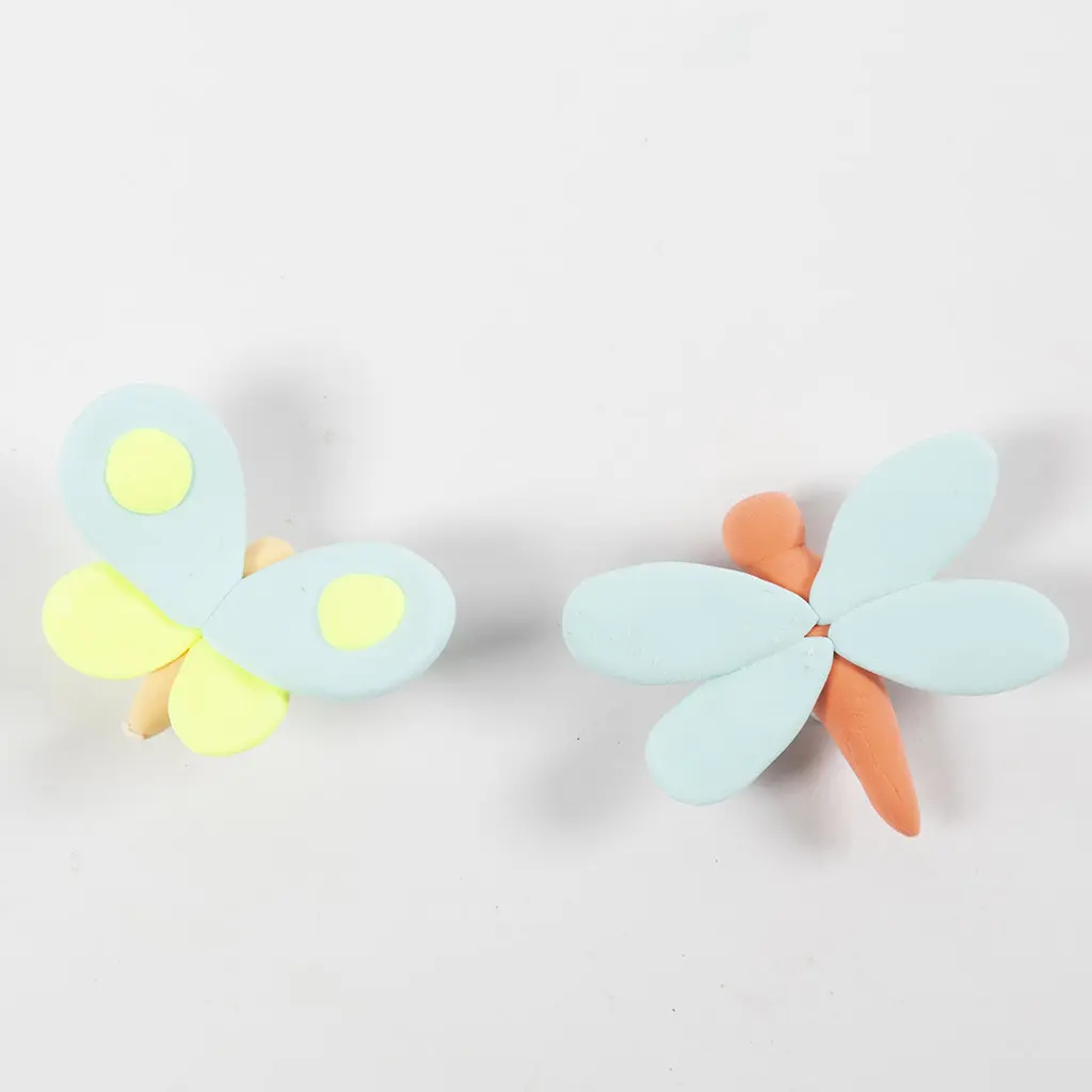 Bovenaanzicht van twee kleiinsecten op een witte achtergrond: een lichtblauw vlindertje met gele accenten en een oranje libelle met lichtblauwe vleugels.