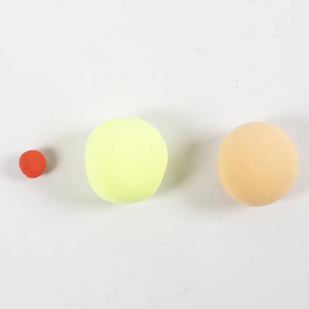 Drie op een rij gelegde kleibolletjes in rood, felgeel en een beige/huidskleurige bol op een witte achtergrond.